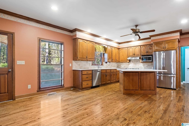 kitchen featuring crown molding, light hardwood / wood-style flooring, stainless steel appliances, and a kitchen island