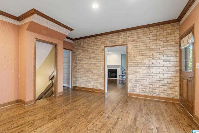 spare room with hardwood / wood-style flooring, brick wall, and ornamental molding