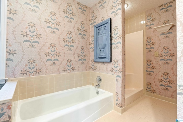 bathroom with a tub to relax in, tile patterned floors, and a textured ceiling