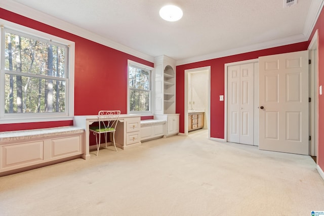 interior space with ornamental molding, light colored carpet, and built in desk