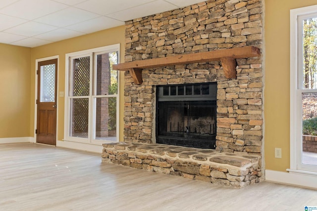 unfurnished living room with hardwood / wood-style flooring, a paneled ceiling, and a fireplace