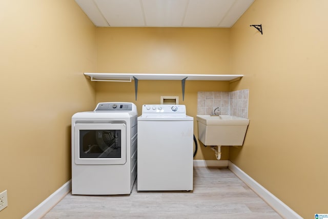 laundry room with light hardwood / wood-style floors, sink, and independent washer and dryer