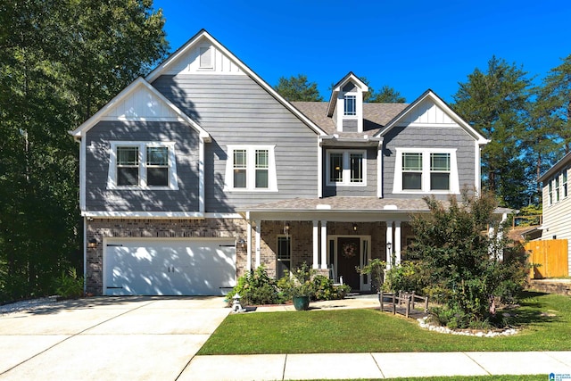 view of front of home featuring a garage, a front yard, and covered porch