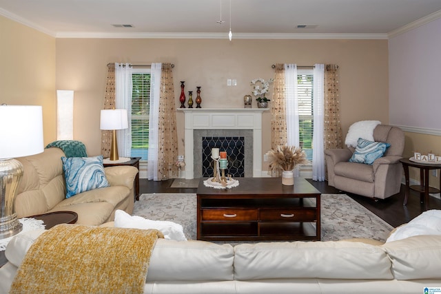 living room with a tiled fireplace, crown molding, and wood-type flooring