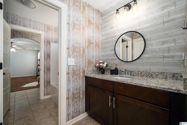 bathroom featuring ceiling fan, tile patterned floors, vanity, and wooden walls