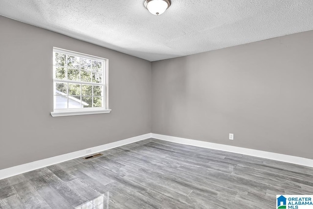 unfurnished room featuring wood-type flooring and a textured ceiling