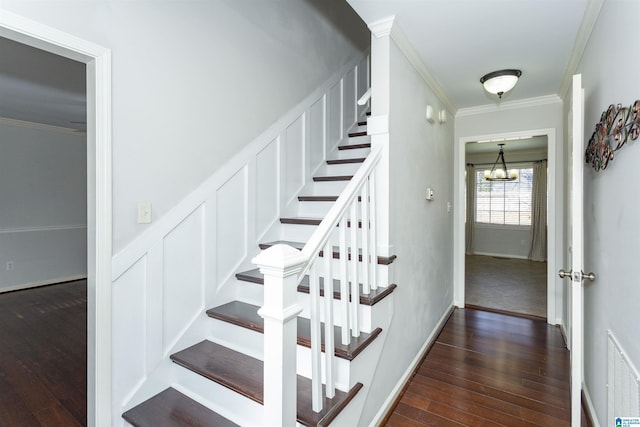 staircase with an inviting chandelier, wood-type flooring, and crown molding