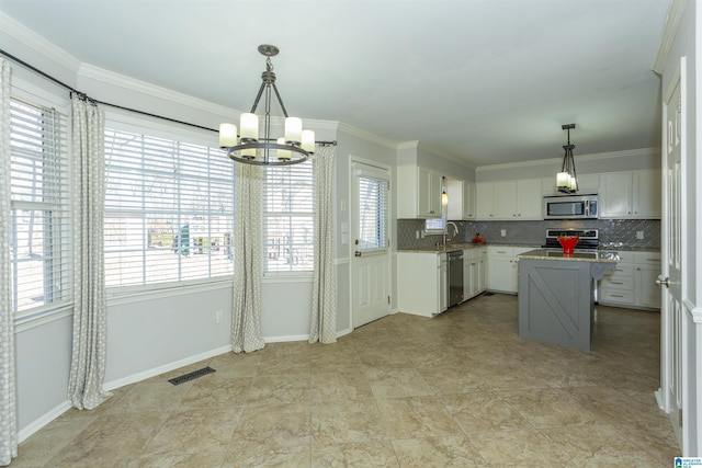 kitchen featuring hanging light fixtures, a kitchen island, white cabinets, and appliances with stainless steel finishes