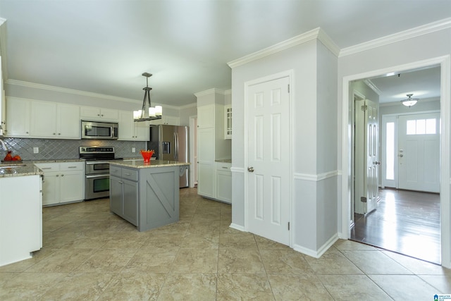 kitchen with decorative light fixtures, a center island, appliances with stainless steel finishes, light stone countertops, and white cabinets