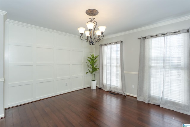 empty room with crown molding, dark hardwood / wood-style floors, and a notable chandelier