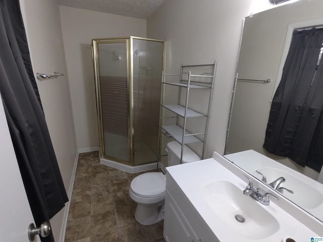 bathroom with a textured ceiling, an enclosed shower, vanity, and toilet