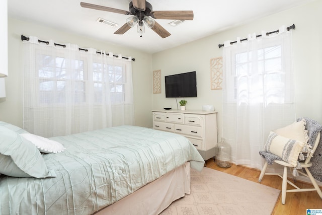 bedroom featuring ceiling fan, light hardwood / wood-style floors, and multiple windows