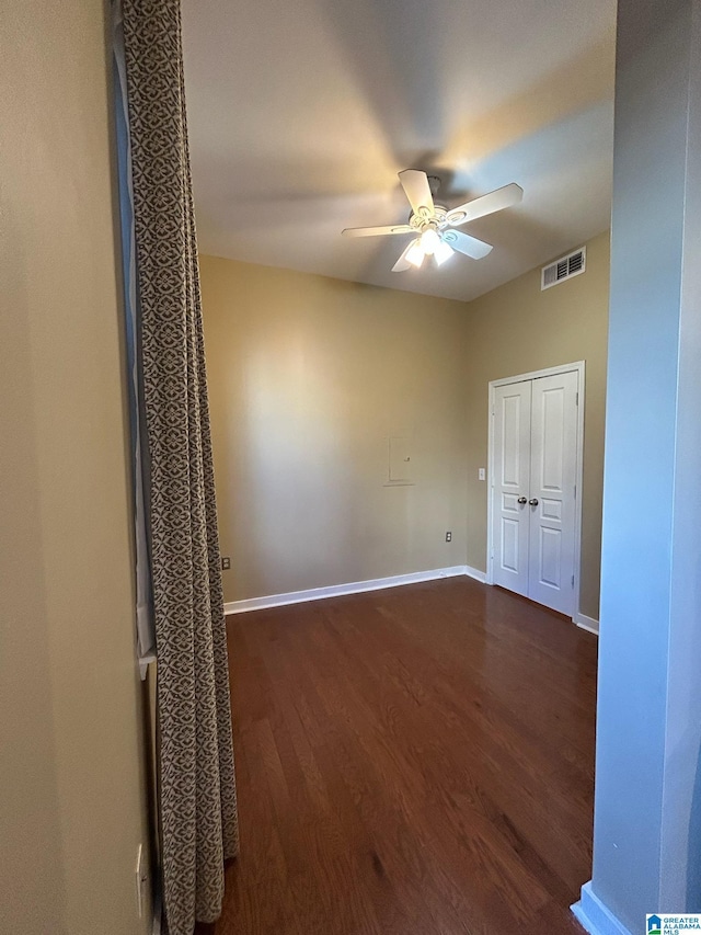 empty room with dark hardwood / wood-style floors and ceiling fan