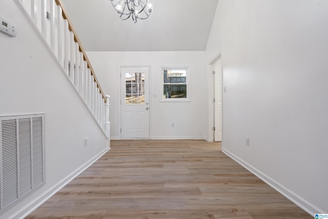 entrance foyer featuring an inviting chandelier, vaulted ceiling, and light hardwood / wood-style floors