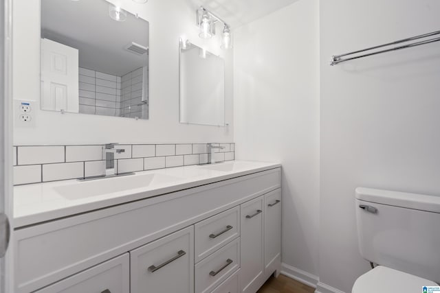 bathroom featuring vanity, decorative backsplash, and toilet