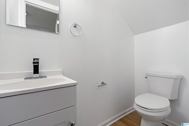 bathroom with vanity, hardwood / wood-style flooring, vaulted ceiling, and toilet