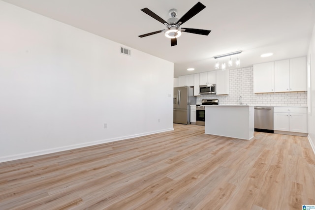 kitchen with tasteful backsplash, light hardwood / wood-style flooring, appliances with stainless steel finishes, a kitchen island, and white cabinets