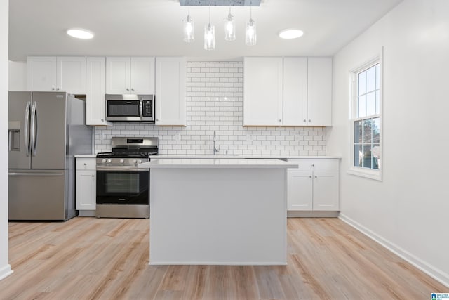 kitchen featuring tasteful backsplash, appliances with stainless steel finishes, hanging light fixtures, and white cabinets