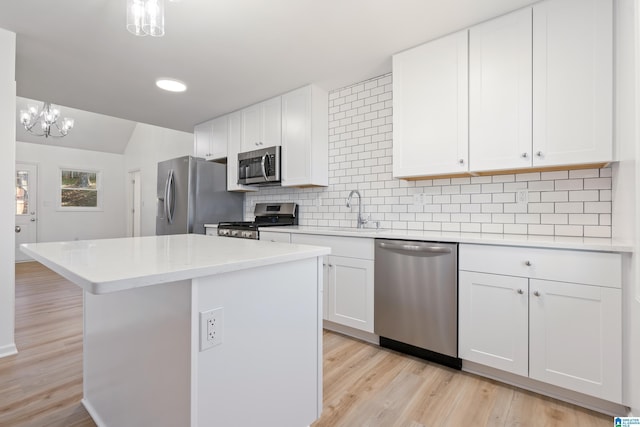 kitchen with pendant lighting, sink, appliances with stainless steel finishes, white cabinetry, and a kitchen island