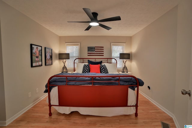 bedroom featuring ceiling fan, light hardwood / wood-style floors, and a textured ceiling