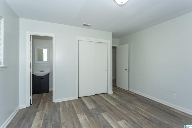 unfurnished bedroom with wood-type flooring, sink, a closet, and connected bathroom