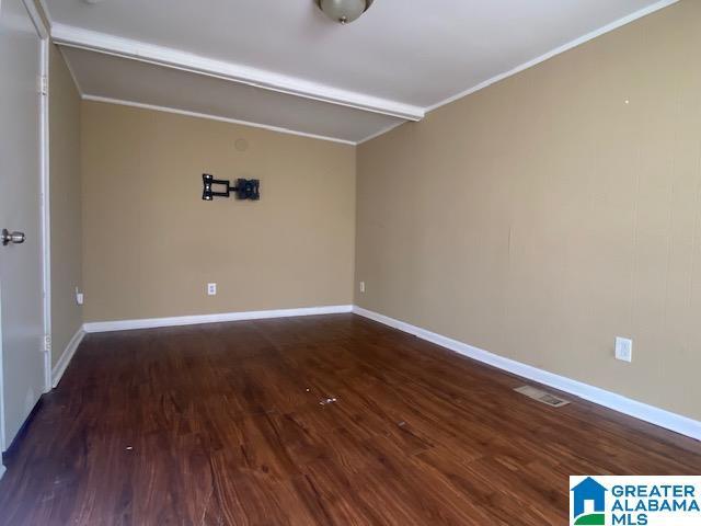 spare room with beamed ceiling, ornamental molding, and dark wood-type flooring