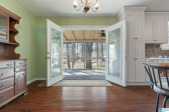 doorway with ceiling fan with notable chandelier, dark wood-type flooring, and a textured ceiling