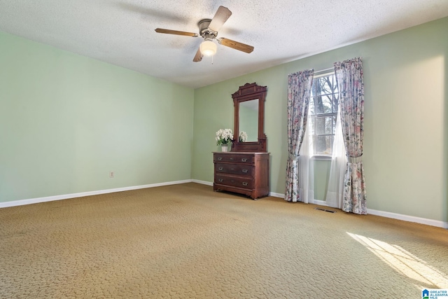 carpeted spare room featuring ceiling fan and a textured ceiling