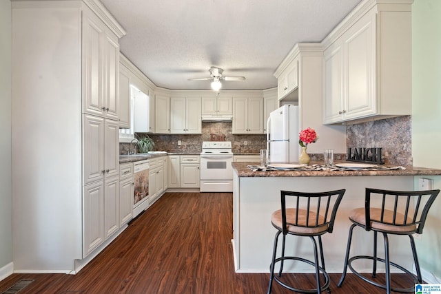 kitchen featuring kitchen peninsula, a kitchen breakfast bar, backsplash, white cabinets, and white appliances