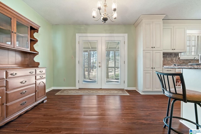 doorway to outside featuring a textured ceiling, dark hardwood / wood-style floors, french doors, and an inviting chandelier