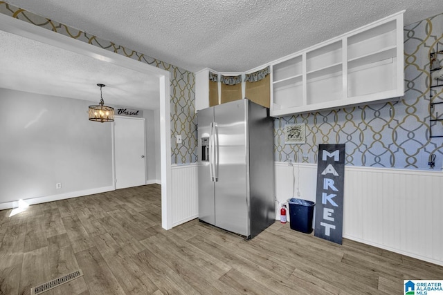 kitchen with hardwood / wood-style floors, a textured ceiling, and stainless steel fridge