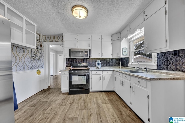 kitchen with decorative backsplash, white cabinets, light wood-type flooring, sink, and stainless steel appliances