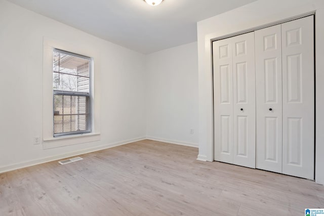 unfurnished bedroom with a closet and light hardwood / wood-style floors