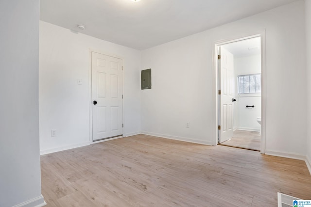 empty room with light hardwood / wood-style floors and electric panel