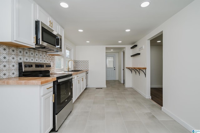 kitchen with decorative backsplash, white cabinets, sink, stainless steel appliances, and wood counters