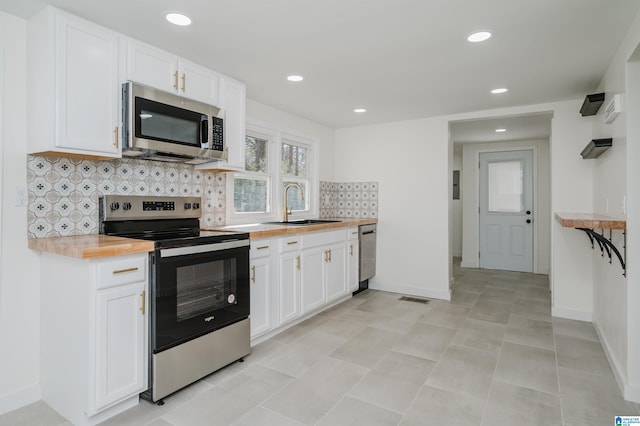 kitchen featuring tasteful backsplash, white cabinetry, sink, stainless steel appliances, and wood counters