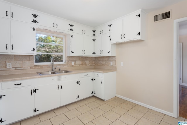 kitchen with white cabinets, backsplash, light tile patterned floors, and sink