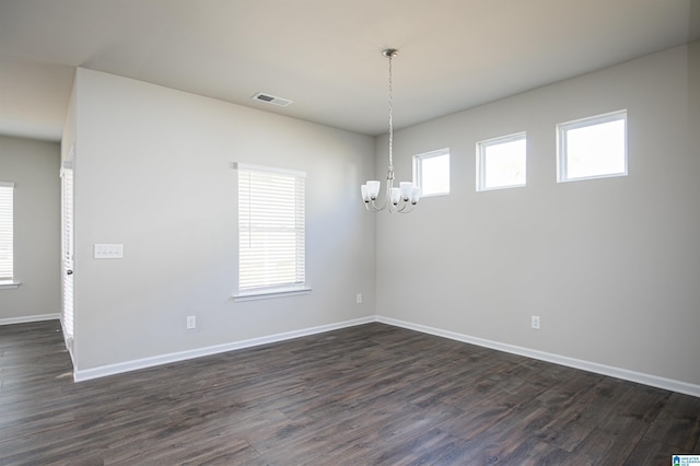 unfurnished room featuring dark wood-type flooring and an inviting chandelier