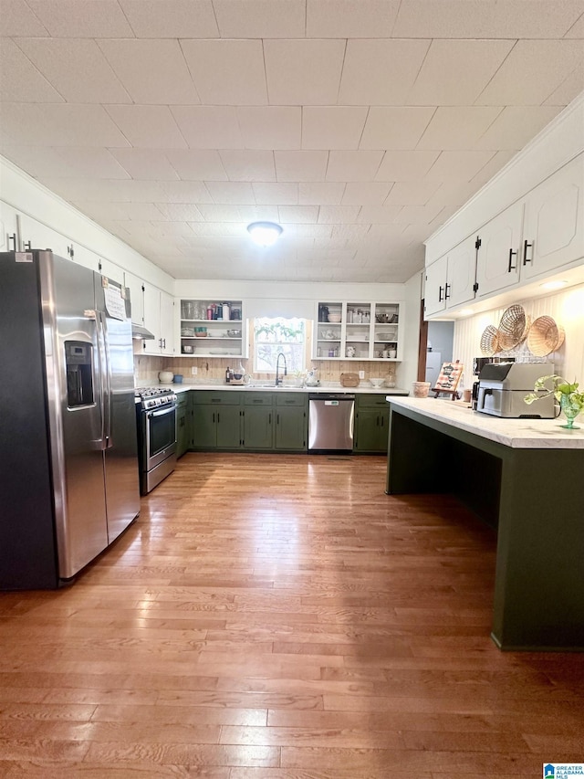 kitchen featuring backsplash, white cabinetry, light hardwood / wood-style flooring, and stainless steel appliances