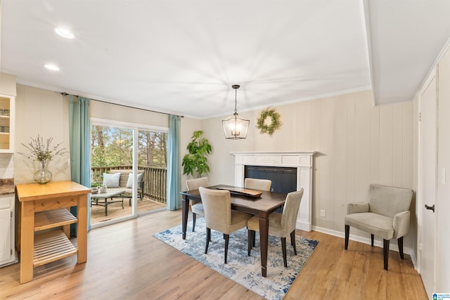 dining area with a notable chandelier, ornamental molding, and light hardwood / wood-style floors