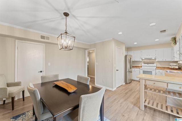 dining area with ornamental molding, sink, and light wood-type flooring