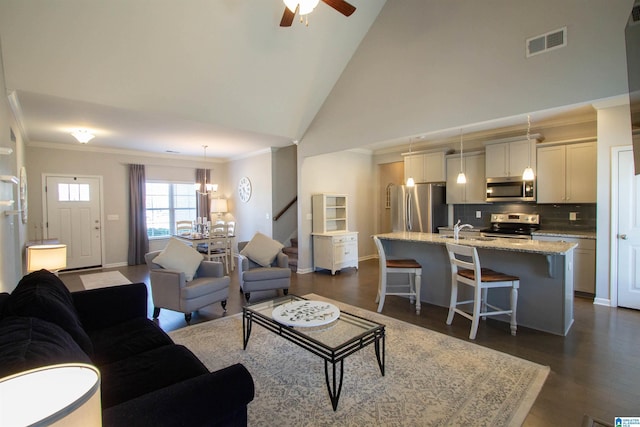 living room with ceiling fan with notable chandelier, sink, dark hardwood / wood-style flooring, and high vaulted ceiling