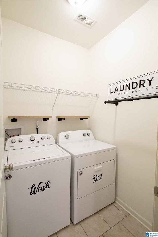 clothes washing area featuring washer and dryer and light tile patterned flooring