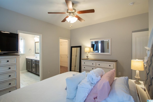 tiled bedroom with sink, ensuite bath, ceiling fan, a walk in closet, and a closet