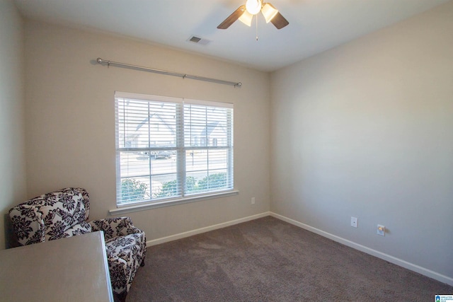 sitting room with ceiling fan and dark carpet