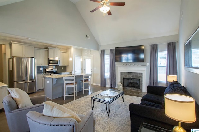 living room with sink, high vaulted ceiling, dark hardwood / wood-style flooring, ceiling fan, and a fireplace