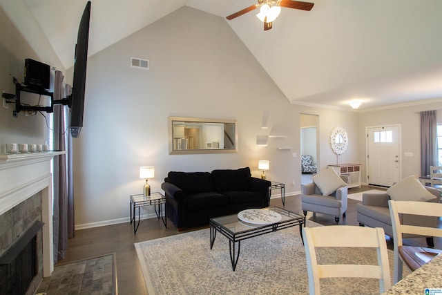 living room featuring dark wood-type flooring, lofted ceiling, crown molding, ceiling fan, and a fireplace