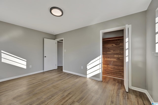 unfurnished bedroom with hardwood / wood-style floors and wood walls