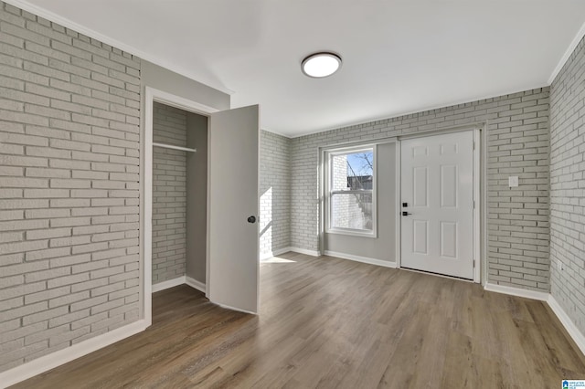 entryway with brick wall and hardwood / wood-style floors