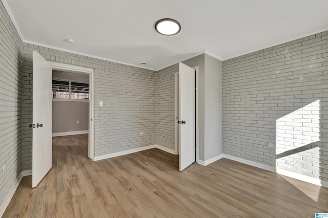 unfurnished bedroom featuring crown molding, brick wall, and light hardwood / wood-style flooring